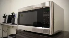 A stainless steel microwave on a counter in an office break room.