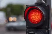 A close-up of a traffic light glowing bright red above a blurred street.
