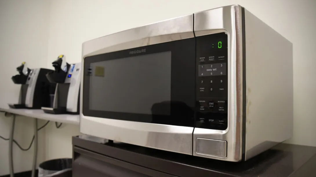 A stainless steel microwave on a counter in an office break room.